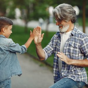 Boy and grandfather are walking in the park. Old man playing with grandson.